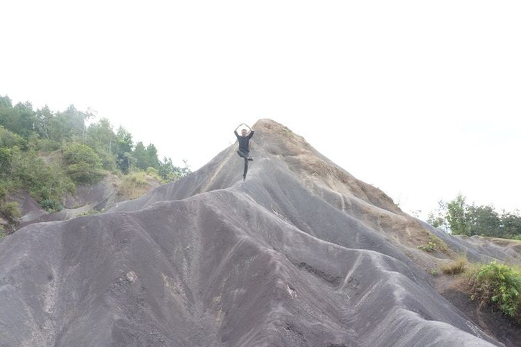 Seorang pengunjung yang melakukan pose foto di atas gumuk pasir.