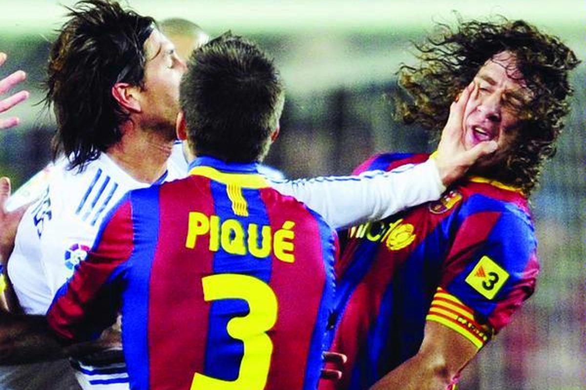 Bek Real Madrid, Sergio Ramos (kiri), yang hilang kendali diri mendorong wajah pemain belakang Barcelona, Carles Puyol, pada menit akhir laga Liga Spanyol di Stadion Nou Camp, Barcelona, Spanyol, Senin (29/11). Beberapa pemain Real Madrid kehilangan kendali akibat dipermalukan Barcelona dengan kekalahan 0-5.