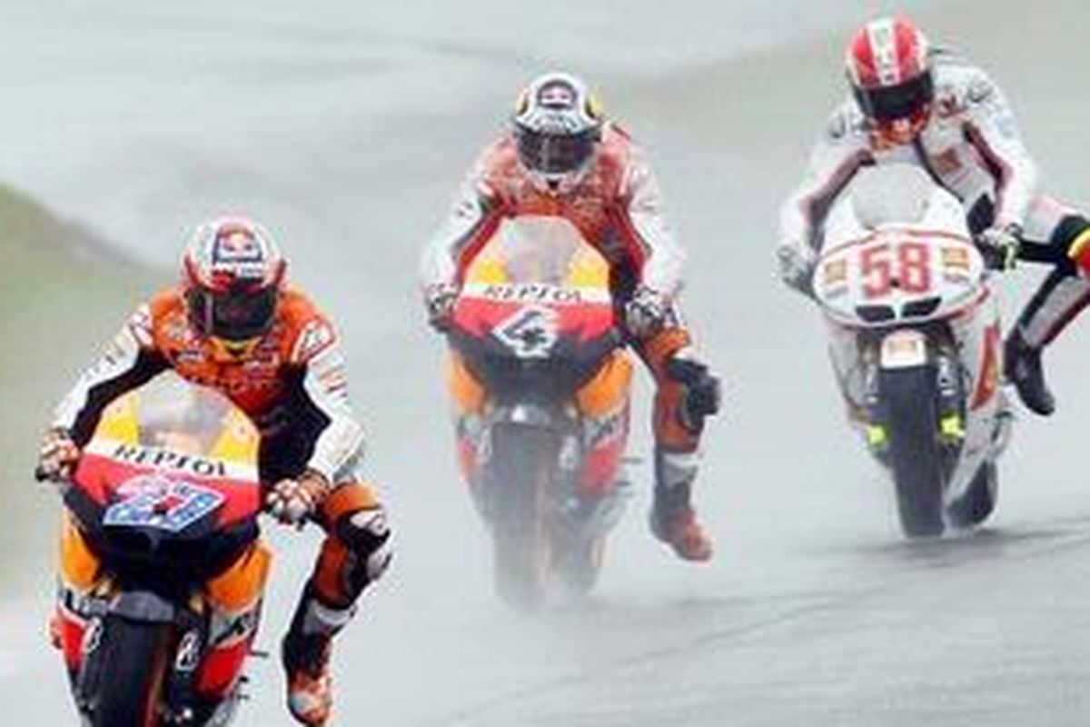 Pebalap Gresino Honda, Marco Simoncelli (kanan) bersaing dengan pebalap Repsol Honda, Andrea Dovizioso (tengah) pada balapan basah di Silverstone, Minggu (12/6/11). Simoncelli akhirnya gagal finis karena jatuh saat pertarungan itu. Sedangkan Casey Stoner (depan) menjadi pemenang.