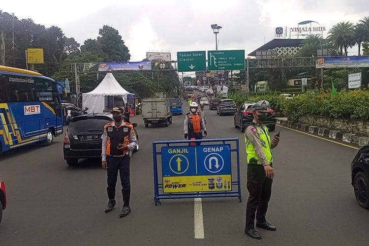 Petugas kepolisian sedang melakukan pengaturan skema ganjil genap di kawasan wisata Puncak Bogor, Jawa Barat.