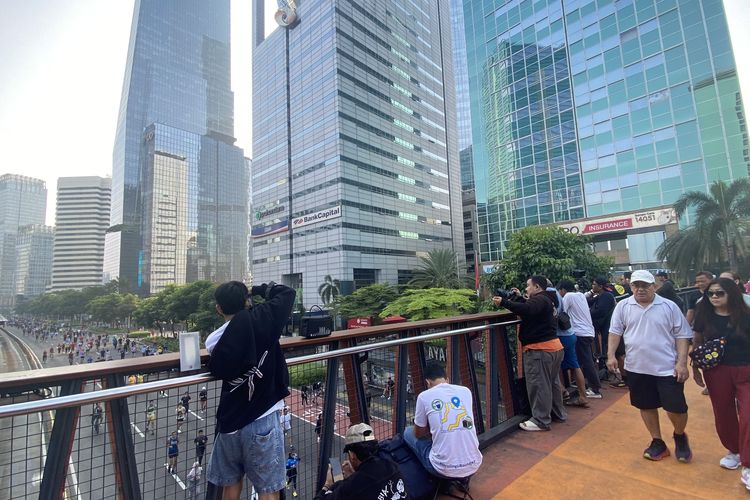 Fotografer pelari berjejer di Jembatan Penyeberangan Orang (JPO) Karet, Jakarta Pusat, Minggu (13/4/2025).