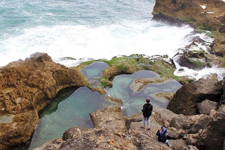 Dua  wisatawan tengah menikmati panorama Pantai Kedung Tumpang di Pucanglaban, Kabupaten Tulungagung, Jawa Timur, Jumat (14/8/2015) sore. Kondisi pantai yang alami, deburan ombak, dan kolam-kolam alami di atas hamparan karang menjadi pesona yang menakjubkan  wisatawan meski infrastruktur masih minim.