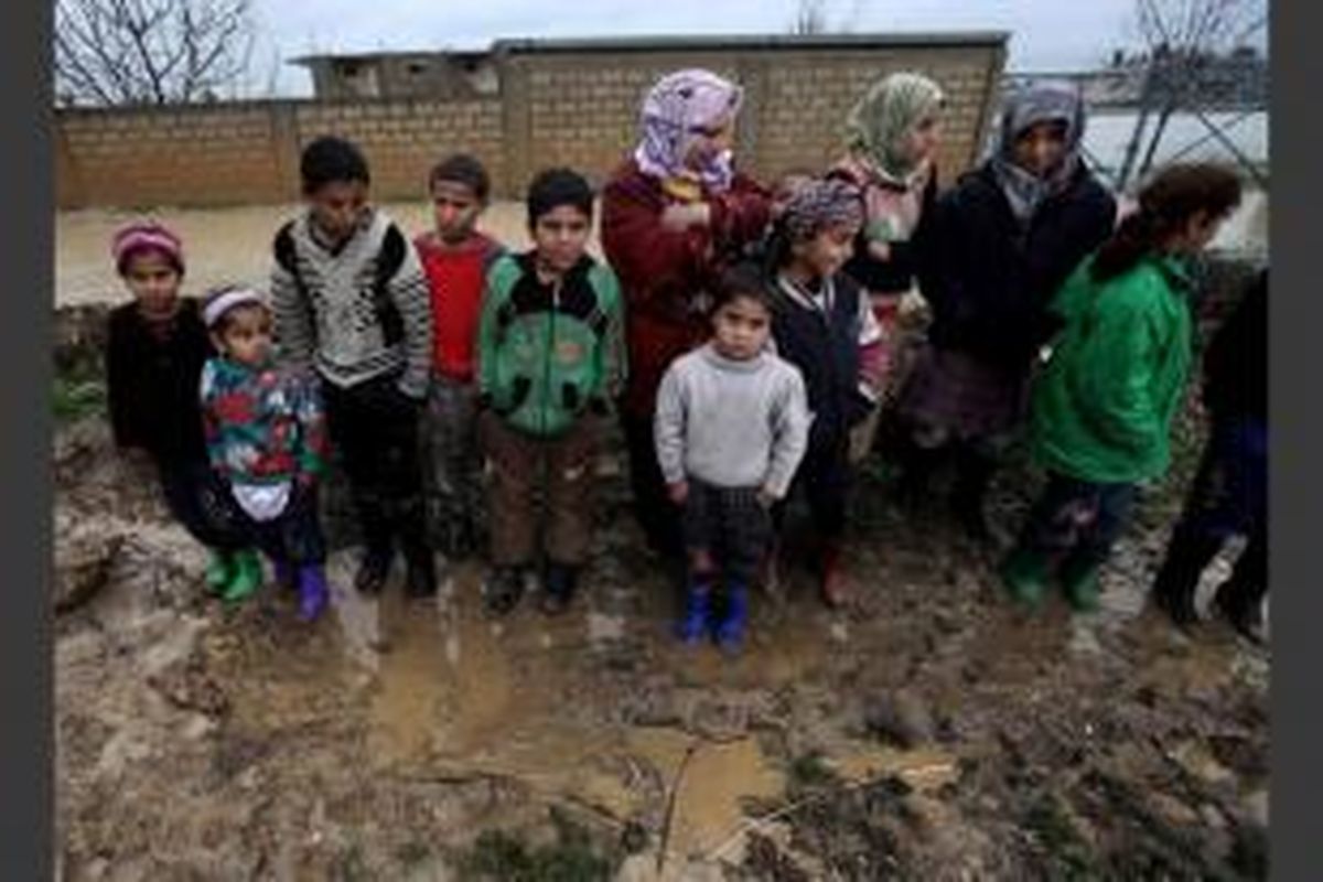 Pengungsi Suriah berkumpul karena tenda mereka kebanjiran akibat hujan, di kamp pengungsi sementara di kota Al-Faour, Lebanon Timur, dekat perbatasan Suriah, 8 Januari 2013.