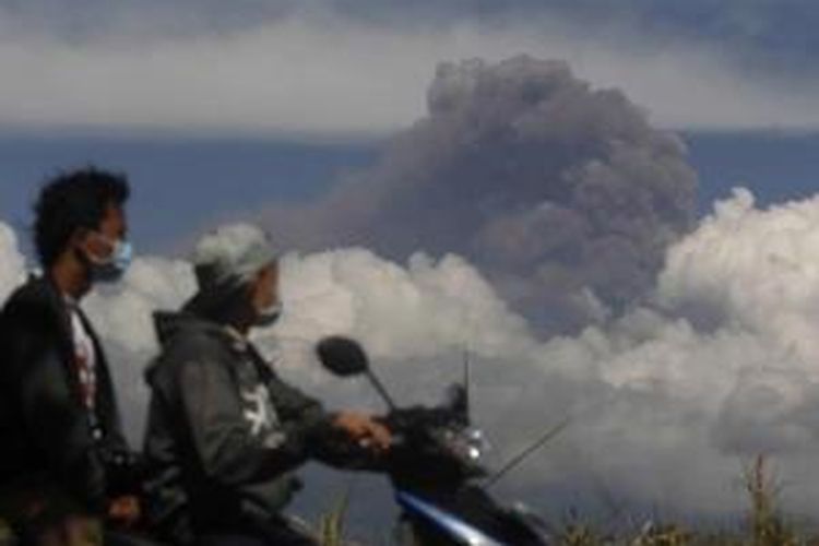 Pengendara melintas dengan latar belakang abu letusan Gunung Raung terlihat dari Melaten, Jawa Timur, 12 Juli 2015. Sejumlah bandara lokal di Jawa Timur dan Bandara Ngurah Rai Bali, sempat ditutup akibat letusan gunung ini.