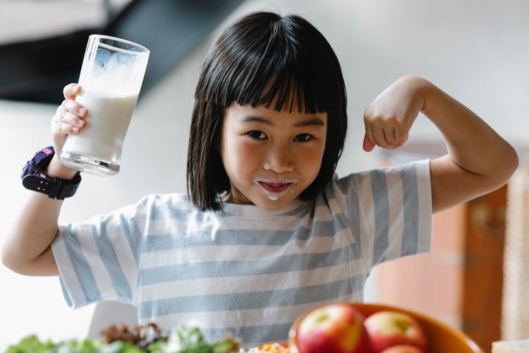 Ilustrasi anak kecil sedang meminum susu.