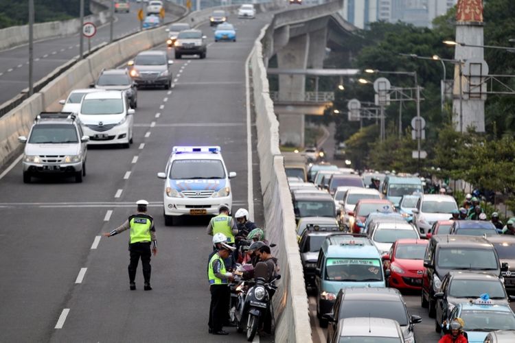 Polisi melakukan razia sepeda motor yang nekat menerobos ke jalan layang non tol (JLNT) Kampung Melayu-Tanah Abang, Jakarta, Selasa (25/7/2017). Pengendara motor masih nekat memasuki dan melintasi JLNT tersebut baik dari arah Tanah Abang maupun Kampung Melayu. KOMPAS IMAGES/KRISTIANTO PURNOMO