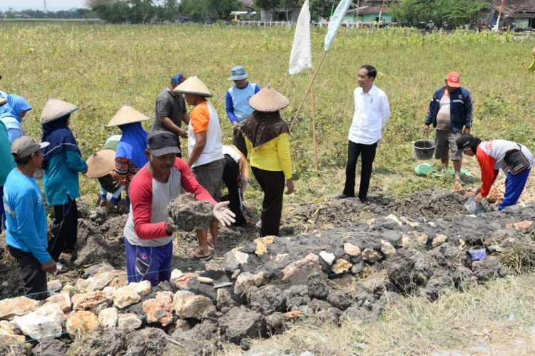 Presiden Joko Widodo (Jokowi) didampingi Menteri Desa, Pembangunan Daerah Tertinggal, dan Transmigrasi (Mendes PDTT) Eko Putro Sandjojo meninjau program Padat Karya Tunai (PKT) pembangunan talud jalan di Desa Tambirejo, Kecamatan Toroh, Kabupaten Grobogan, Jawa Tengah, Sabtu (15/9/2018)