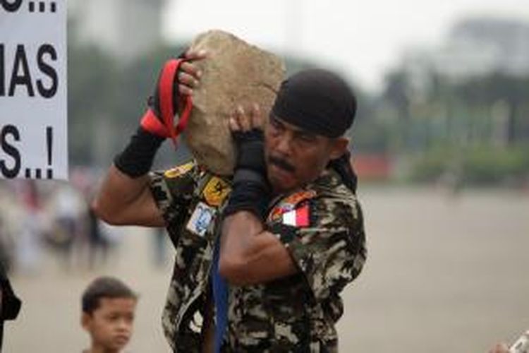 Kopral Bagyo memikul batu saat berjalan memutari Tugu Monumen Nasional di Jakarta, Sabtu (06/07/2013). Kopral Bagyo berencana untuk memutari monas selama 25 jam dalam rangka hari ulang tahun Polisi Militer dan kampanye hidup sehat tanpa narkoba. 