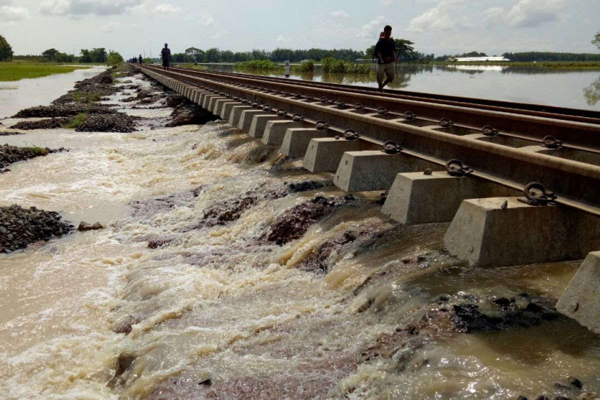 Tampak warga melintas di atas rel yang dibawahnya terdapat arus deras yang merupakan aliran dari luapan Sungai Cisanggarung di Kecamatan Ciledug , Cirebon, Jawa Barat.