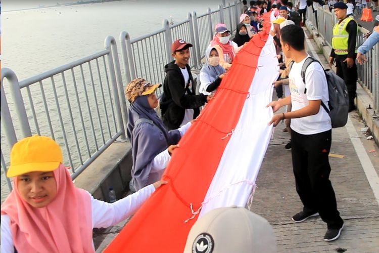 Bendera merah putih sepanjang 5,4 kilometer dibentangkan saat kampanye keselamatan berkendara di Jembatan Suramadu, Minggu (17/3/2019)