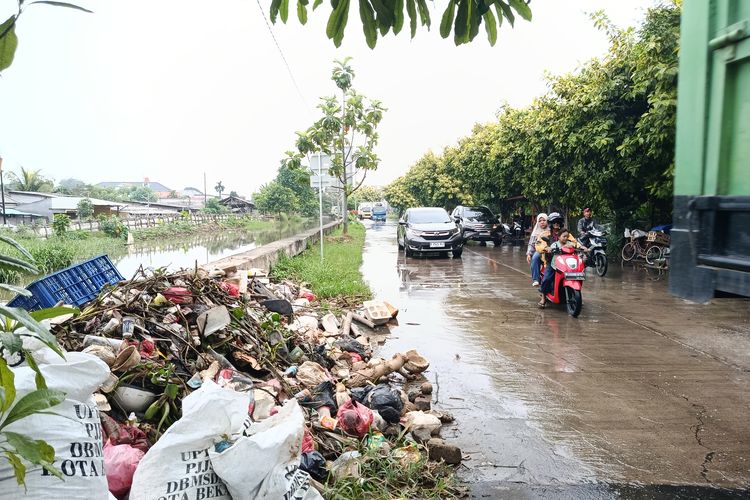 Sampah Menumpuk di Kali Babelan, Jalan Duta Harapan Bekasi Tergenang dan Licin