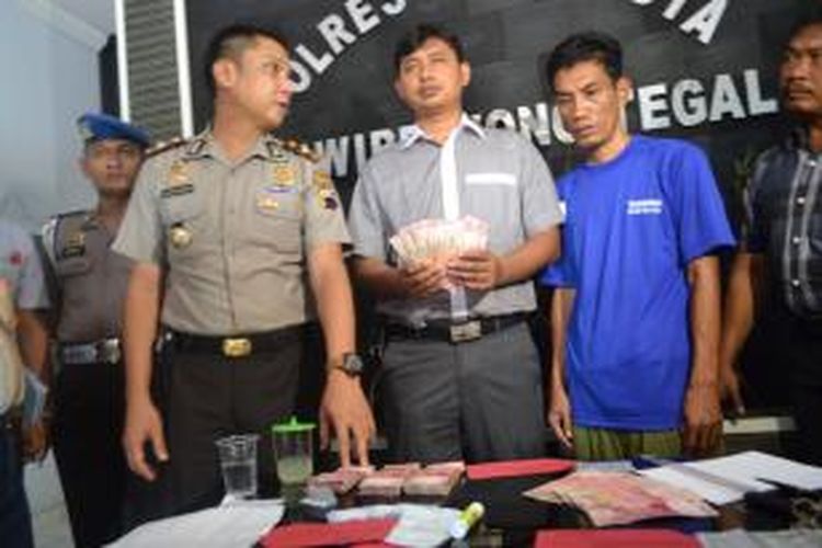 Polisi menunjukkan barang bukti uang yang disita polisi dari AY, pria yang mengaku bisa menggandakan uang hingga lima kali lipat di Aula Mapolres Tegal Kota, Jawa Tengah, Selasa (07/01/2014).