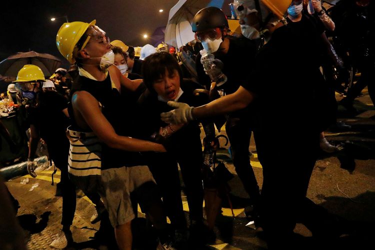 Massa di Hong Kong membobong rekannya ketika polisi menembakkan gas air mata untuk merebut gedung parlemen pada Senin (1/7/2019) di tengah krisis politik yang mendera sepanjang tiga pekan terakhir.