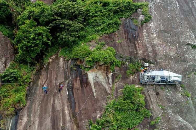 Reporter Kompas.com dibantu pemandu menyeberangi tyrolean untuk mencapai hotel gantung Padjajaran Anyar yang terletak di tebing Gunung Parang, Purwakarta, Jawa Barat setinggi 500 meter difoto menggunakan drone, Minggu (19/11/2017). Hotel gantung ini diklaim sebagai hotel gantung tertinggi di dunia mengalahkan ketinggian hotel gantung di Peru.  