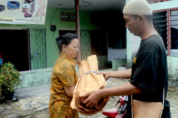 Pekerja memberikan  bahan baku kulit kayu pohon terap (Artocarpus odoratissimus) kepada perajin di Tarakan, Kalimantan Utara. 