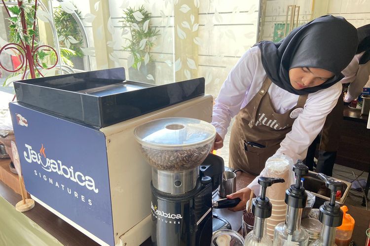 Barista tuli, Della sedang melakukan tamping untuk memadatkan bubuk kopi yang akan diraciknya. 