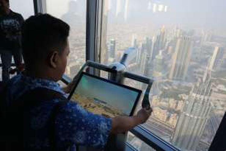 Turis tengah memindai kota Dubai dengan alat yang tersedia di lantai 125 Burj Khalifa