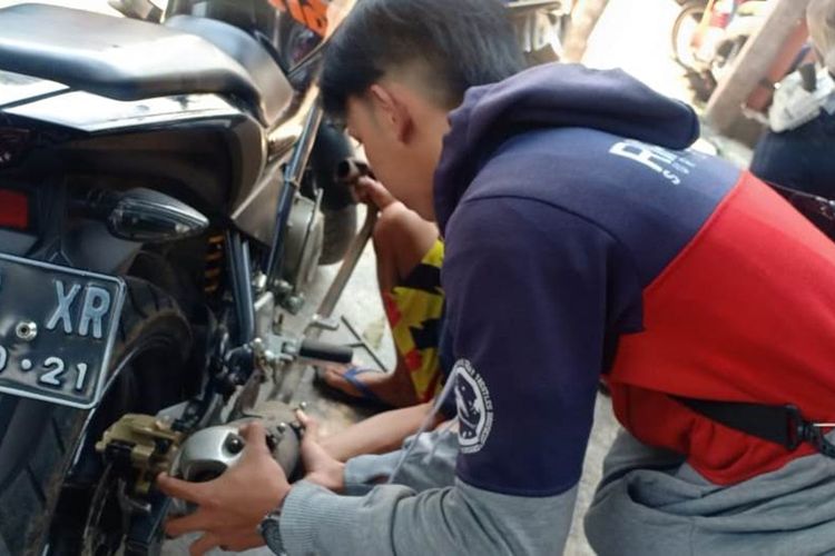 Seorang pengendara sepeda motor mencopot knalpot bising dihadapan polisi saat terjaring razia, Rabu (20/11/2019). Selain ditilang, pelanggar tersebut disuruh membuat pernyataan tertulis di atas meterai untuk tidak memakai kembali knalpot bising tersebut.