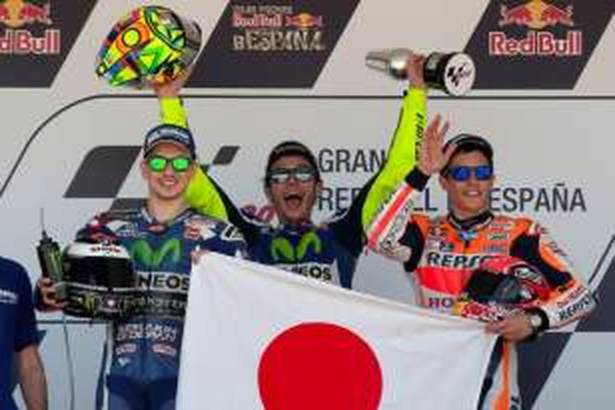 Pebalap Movistar Yamaha asal Spanyol, Jorge Lorenzo (kiri), dan pebalap Repsol Honda asal Spanyol, Marc Marquez (kanan), memegang bendera Jepang saat berdiri di atas podium Sirkuit Jerez setelah balapan GP Spanyol, Minggu (24/4/2016). Pebalap Movistar Yamaha asal Italia, Valentino Rossi (tengah), finis di urutan pertama.