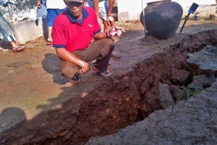 Ratakan tanah akibat penambangan batu bata di bagian bawah bangunan rumah milik Fathorrozi, Desa Grujugan, Pamekasan, Jumat (21/6/2013)