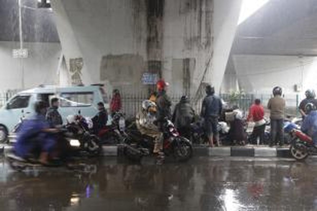 Pengendara motor berteduh di bawah jembatan di kawasan Slipi, Jakarta, Jumat (14/11/2014). Badan Meteorologi, Klimatologi, dan Geofisika (BMKG) memperkirakan wilayah DKI Jakarta diguyur hujan dengan intensitas ringan hingga sedang pada siang hingga malam hari. KOMPAS IMAGES/RODERICK ADRIAN MOZES