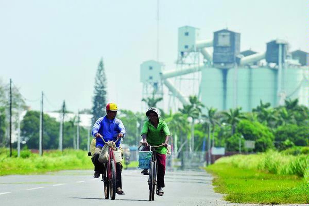 Dua nelayan, Abdul Wahab (52) dan Usman (55), bersepeda sepulang mencari ikan di laut dengan latar belakang bangunan pabrik PT Indonesia Asahan Aluminium (Inalum) di Kabupaten Batu Bara, Sumatera Utara, Senin (6/2). Banyak pihak menolak perpanjangan pengolahan PT Inalum oleh Pemerintah Jepang dengan alasan Indonesia akan lebih banyak meraup keuntungan jika perusahaan tersebut dikelola secara mandiri.