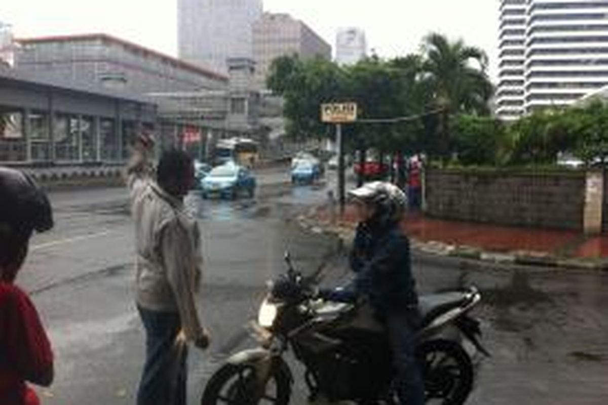 Pengendara motor diberhentikan karena hendak melintas Jalan MH Thamrin, Jumat (26/12/2014).