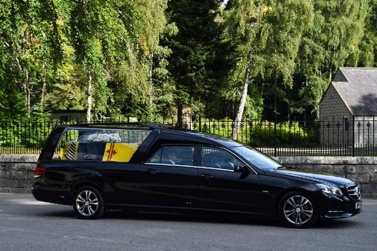 Mobil jenazah yang membawa peti mati Ratu Elizabeth II ditutupi simbol Royal Standard of Scotland dan bunga keluar dari Kastil Balmoral di Ballater, 11 September 2022. Peti mati Ratu Elizabeth II akan melakukan perjalanan darat melalui kota-kota dan desa-desa Skotlandia saat memulai perjalanan terakhirnya dari tempat peristirahatan di Balmoral, Skotlandia. Ratu Elizabeth II wafat pada 8 September 2022, akan dibawa ke Istana Holyrood House sebelum beristirahat di Katedral St Giles lalu melanjutkan perjalanan ke London untuk pemakamannya. 