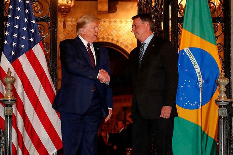 President AS Donald Trump bersalaman dengan Presiden Brasil Jair Bolsonaro di Mar-a-Lago, Palm Beach, Florida, Amerika Serikat (7/3/2020). Setelah kunjungan ini, Sekretaris Bolsonaro dinyatakan positif virus corona.