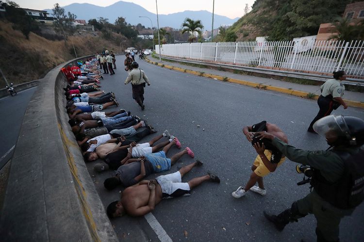 Warga ditangkap oleh pasukan keamanan berbaring di jalan setelah penjarahan terjadi saat pemadaman berlangsung di Caracas, Venezuela, Minggu (10/3/2019). Di tengah krisis yang melanda Venezuela, pemadaman listrik massal yang terjadi berhari-hari di sejumlah kawasan negara itu menimbulkan banyak kekacauan seperti penjarahan hingga kesulitan air.