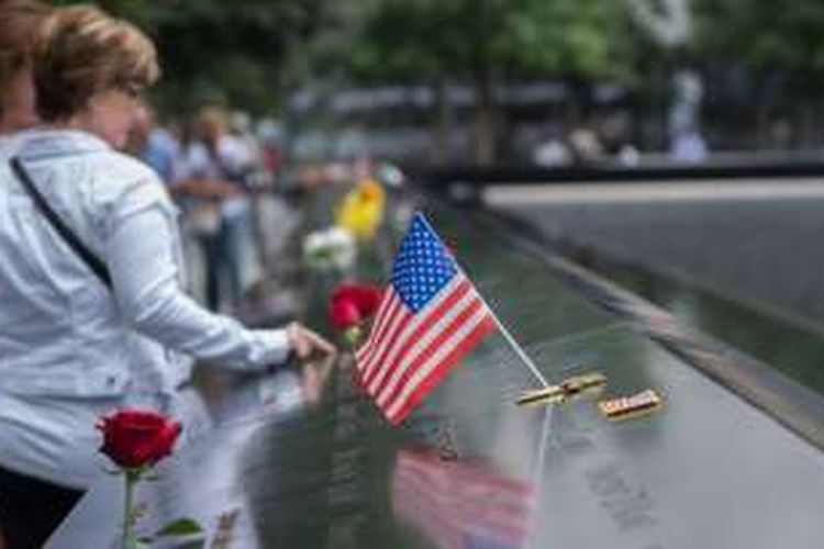 Para pengunjung menyentuh nama-nama korban tewas dalam serangan terhadap gedung World Trade Center di New York, AS, 11 September 2001 pada peringatan 15 tahun serangan teror itu, Minggu (11/9/2016).
