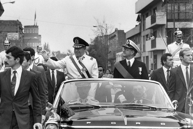 Foto tak bertanggal menunjukkan Jenderal Augusto Pinochet (kiri) saat berkuasa sebagai Presiden Chile, melambaikan tangannya dalam pawai mobil di ibu kota Santiago bersama Menteri Pertahanan Wakil Laksamana Patricio Carvajal (kanan). Pinochet mengambil alih kekuasaan pada 11 September 1973 setelah kudeta militer yang menewaskan Presiden Salvador Allende.