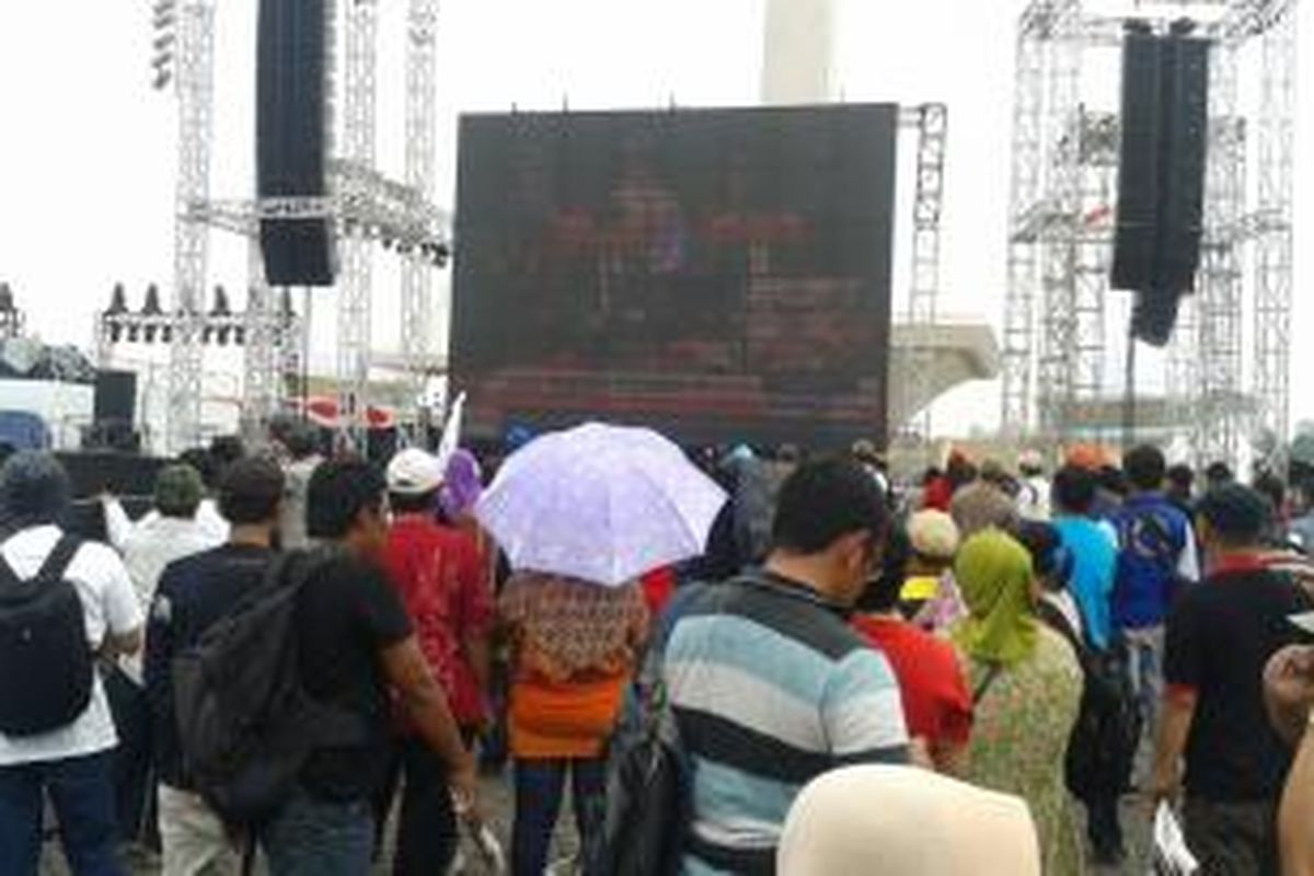 Para relawan menyaksikan acara pelantikan Jokowi-JK menjadi presiden-wakil presiden melalui layar yang dipasang di panggung utama Syukuran Rakyat Salam 3 Jari di Monas, Jakarta Pusat, Senin 920/10/2014).