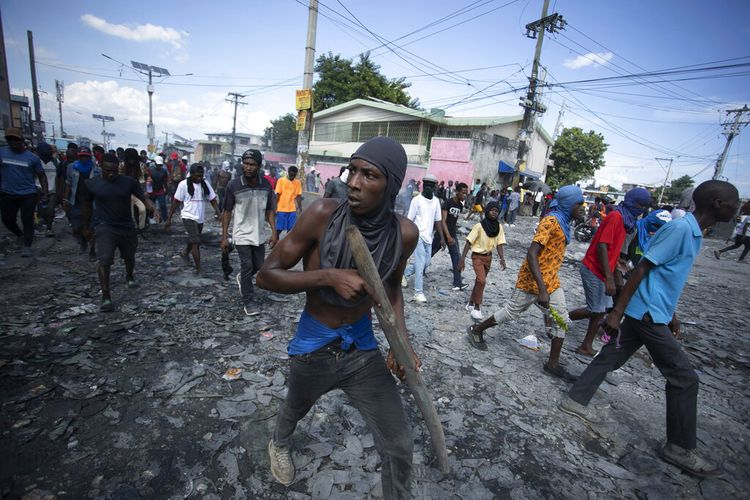 Seorang pengunjuk rasa membawa sepotong kayu simulasi senjata selama protes menuntut pengunduran diri Perdana Menteri Ariel Henry, di daerah Petion-Ville Port-au-Prince, Haiti, Senin, 3 Oktober 2022. 