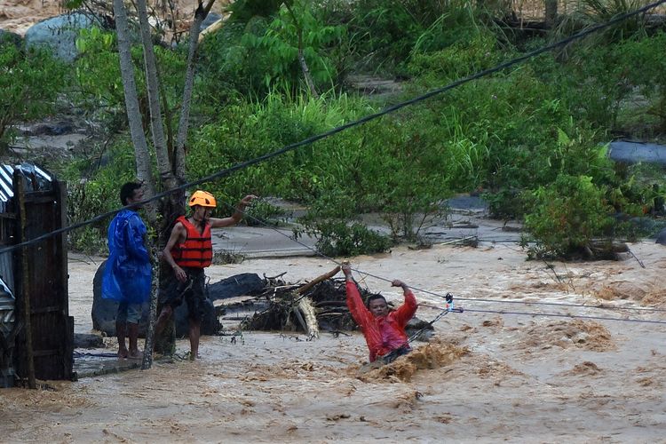 Tim SAR memandu warga menyeberangi air menggunakan tali di kawasan Batu Busuk, Pauh, Padang, Sumatera Barat, Minggu (14/12/2025). Air sungai di permukiman terdampak banjir bandang tersebut kembali meluap dan membuat sejumlah warga dievakuasi ke tempat yang lebih aman. 