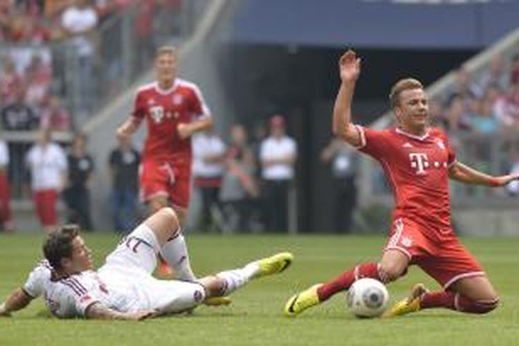 Pemain Nuremberg, Daniel Ginczek (kiri), melanggar gelandang Bayern Muenchen, Mario Goetze, dalam pertandingan Bundesliga.