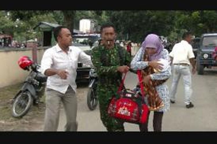 Seorang anggota TNI melindungi seorang ibu yang menggendong bayi ketika terjadi bentrokan antara massa dengan aparat TNI di depan markas Kodim 01/01 BS, Banda Aceh, Senin (16/12/2013).