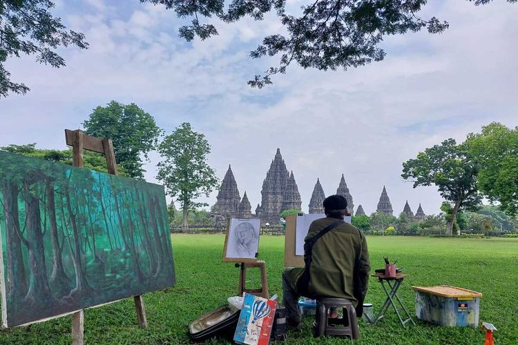 Seorang pelukis saat melukis di Taman area Candi Prambanan. Ada sembilan orang pelukis yang dihadirkan untuk mengabadikan Prambanan Dalam Sunyi dalam karya lukis, Senin (11/3/2024)