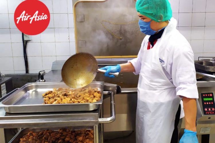 Staf produksi inflight meals AirAsia menggunakan APD dalam menyiapkan pesananan makanan untuk penumpang.