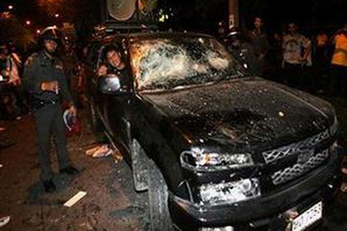 Polisi Thailand memindahkan sebuah kendaraan yang rusak akibat pertikaian aparat keamanan dengan demonstran antikudeta di dekat kediaman Prem Tinasulanond, penasehat terkemuka kerajaan, di Bangkok, 22 Juli 2007. 