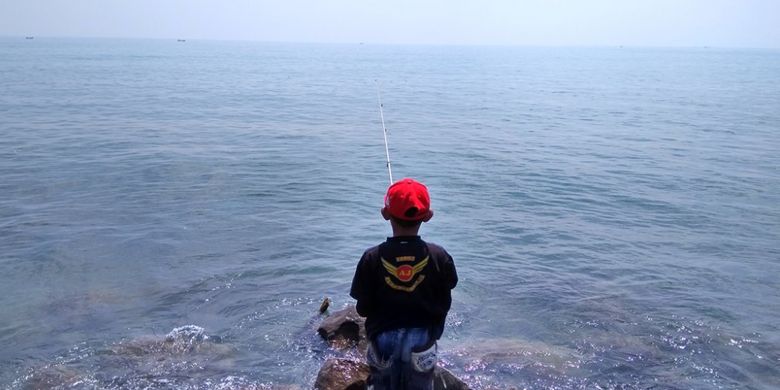 Seorang anak memancing di pinggiran pantai Desa Hagu Barat Laut, Kecamatan Banda Sakti, Lhokseumawe, Aceh, Minggu (23/7/2017).