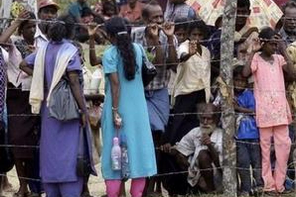 Warga sipil Tamil berdiri di balik kawat berduri kamp pengungsi.