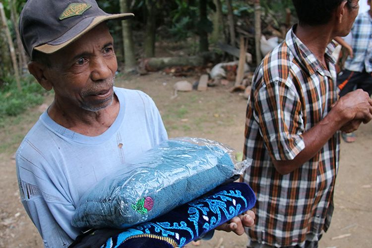 Usman (65) warga Desa Pulo Teungoh, Kecamatan Makmur, Kabupaten Bireuen, Aceh menerima baju koko, kain sarung, dan perlengkapan shalat yang diberikan Bripka Deni Putra saat menyerahkan kunci rumah panggung yang dibangunnya dengan menggunakan uang hasil menjual motor trail kesayangannya di facebook beberapa pekan lau.