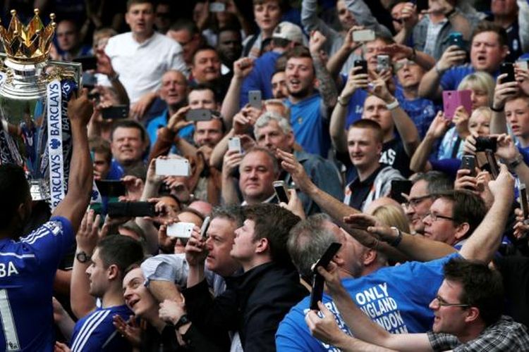 Penyerang Chelsea, Didier Drogba, saat mengangkat trofi Premier League di depan pendukungnya seusai mengalahkan Sunderland 3-1 pada laga terakhir Premier League 2014-15 di Stamford Bridge, Minggu (24/5/2015). 