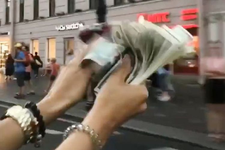 Dalam potongan video, terlihat tangan salah satu remaja membawa setumpuk uang sebelum kemudian membuangnya di jalan.