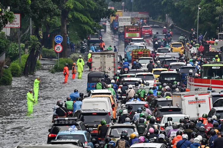 Petugas Kepolisian bersama Dinas Perhubungan mengatur lalu lintas kendaraan yang terjebak kemacetan saat melintasi genangan air di Cawang, Jakarta, Rabu (4/2/2026). Curah hujan tinggi dan buruknya perawatan drainase menyebabkan genangan air merendam jalan DI Panjaitan dengan ketinggian 10-30 cm. 