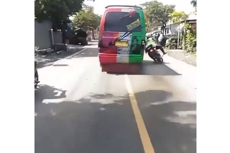 Tangkapan layar video yang menampilkan seorang polisi yang mengendarai sepeda motor trail lalu ditabrak secara sengaja oleh sopir mobil elf.