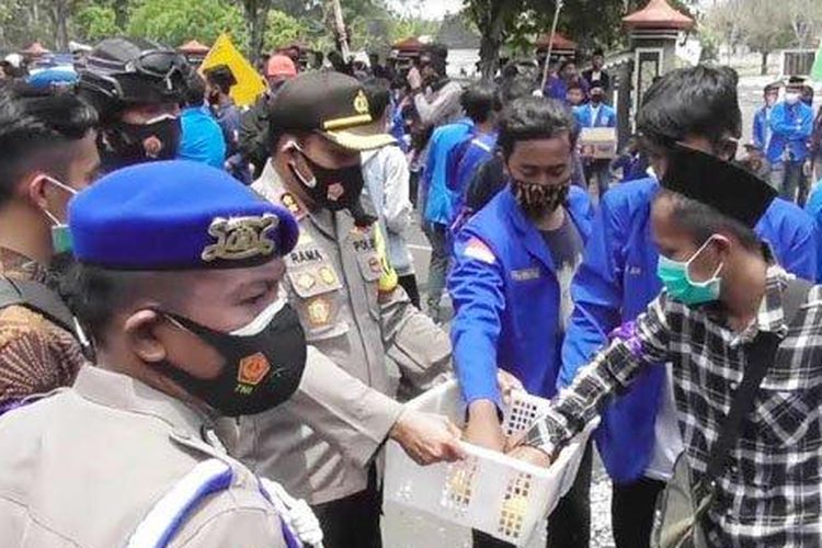 Kapolres Bangkalan, AKBP Rama Samtama Putra membagikan buah jeruk ketika massa PMII Bangkalan menggelar aksi demo penolakan Omnibus Law UU Cipta Kerja di depan Gedung DPRD Bangkalan, Jumat (9/10/2020). 
