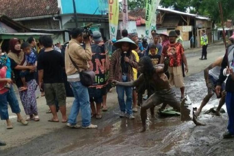Sejumlah warga melakukan aksi teatrikal didalam kubangan lumpur di ruas jalan Tegal-Purwokerto di Tonjong, Brebes, Jawa Tengah, Jumat (20/1/2017).