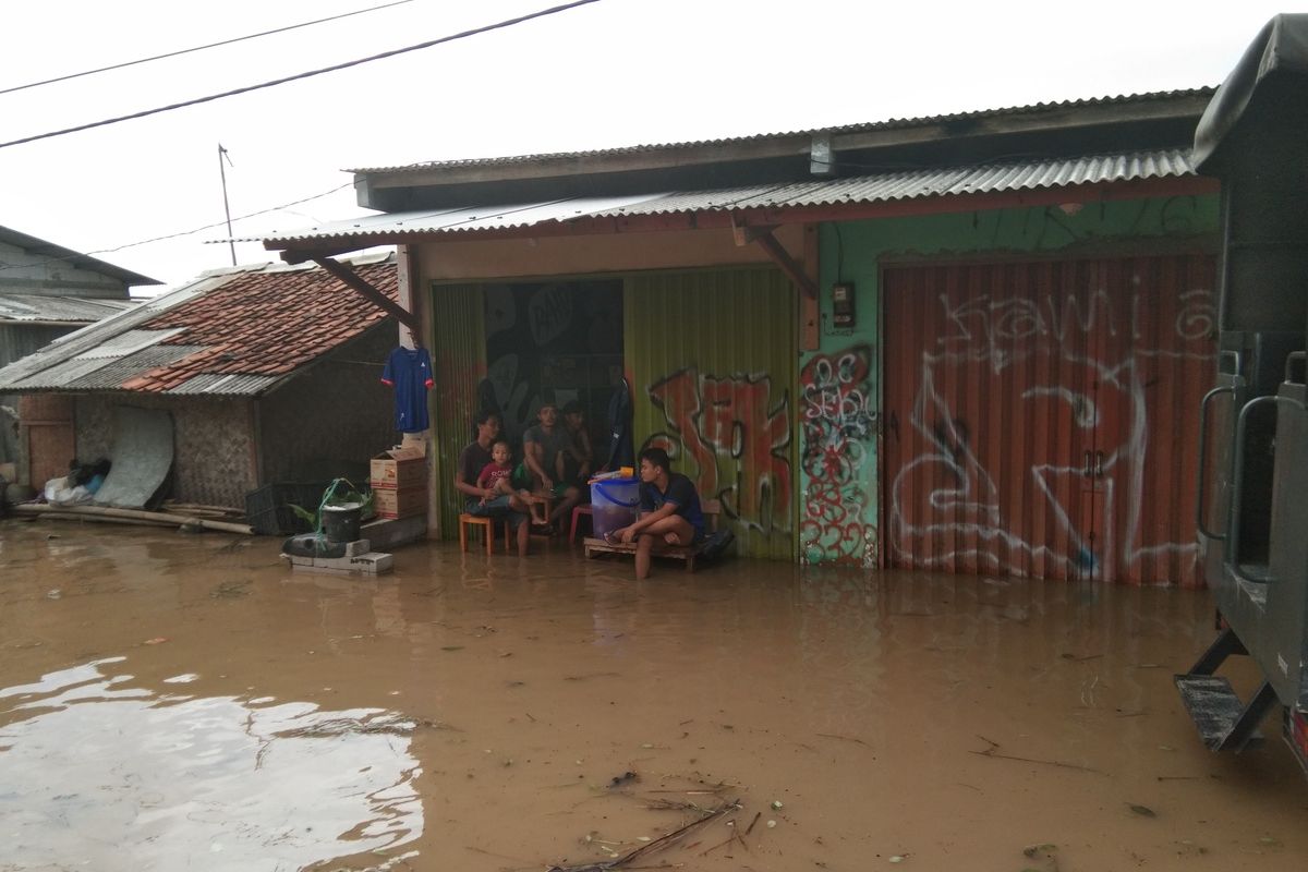 Sejumlah warga tengah duduk di rumah yang terdampak banjir di Dusun Pengasinan Desa Karangligar, Kecamatan Telukjambe Barat, Kabupaten Karawang, Rabu (1/1/2019).